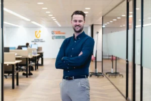 Tobias Bas op kantoor zoetermeer in de gang met een blauw overhemd